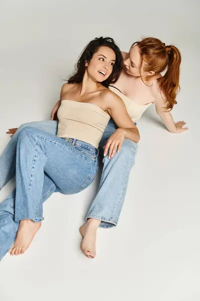 Deux femmes élégantes allongées sur le sol, les bras l'une autour de l'autre dans une étreinte aimante. — Photo de stock
