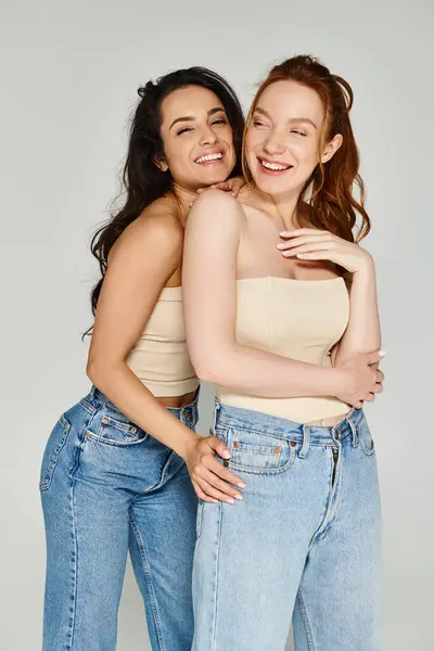 Two young women in elegant attire hug each other tightly, beaming with happiness. — Stock Photo