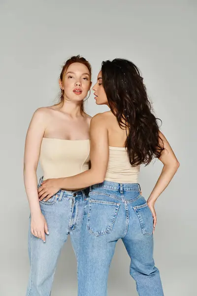 Two women, a loving lesbian couple, stand side by side in stylish jeans. — Stock Photo