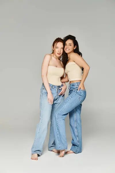Two women in jeans, a loving lesbian couple, standing together happily. - foto de stock