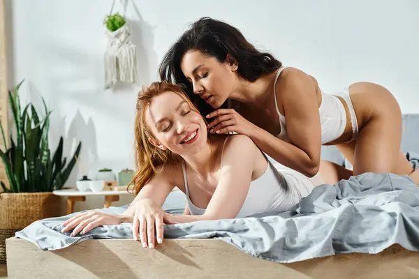 Two elegant women in love recline on a luxurious bed, sharing a moment of intimacy. — Stock Photo