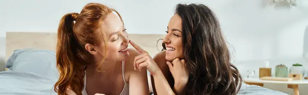 Dos mujeres en trajes elegantes acostadas en la cama, sonriendo alegremente. - foto de stock