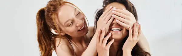 Two laughing women in elegant attire covering their faces in delight. — Stock Photo