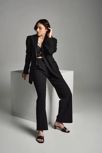 Eine schöne Plus-Size-Frau im schwarzen Anzug posiert selbstbewusst für ein Foto vor grauem Hintergrund. — Stockfoto