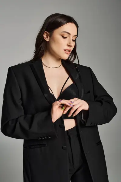 Stylish plus size woman striking a pose in a black suit and a bold choke necklace against a gray backdrop. — Stock Photo