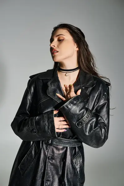 Une belle femme taille plus frappe une pose dans une veste en cuir noir élégant et choker à la mode sur un fond gris. — Photo de stock