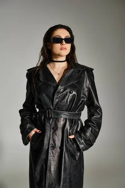 Uma mulher deslumbrante plus size exibe estilo e sofisticação em um casaco de trincheira de couro preto contra um pano de fundo cinza. — Fotografia de Stock