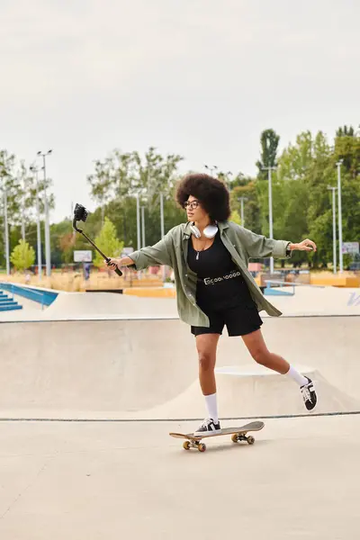 Eine junge Afroamerikanerin mit lockigem Haar fährt selbstbewusst auf einem Skateboard in einem lebhaften Skatepark und zeigt ihr Können. — Stockfoto