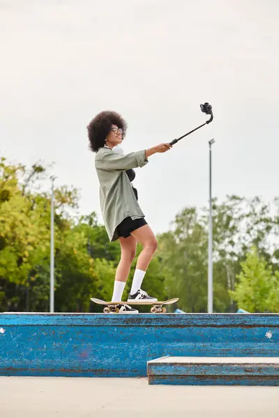 Uma jovem afro-americana com cabelo encaracolado desliza suavemente por uma rampa de skate em um parque de skate ao ar livre. — Fotografia de Stock