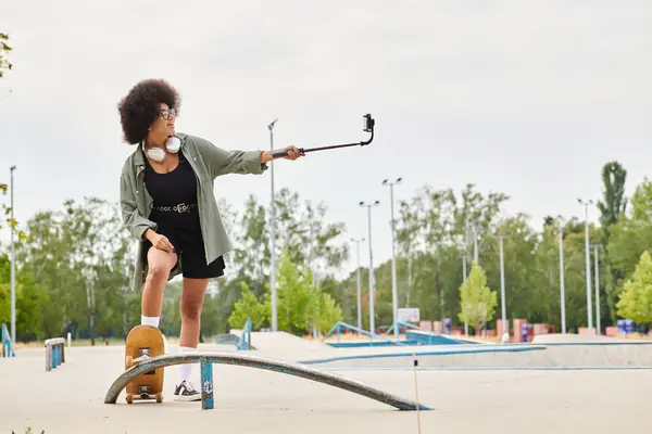 Eine junge Afroamerikanerin mit lockigem Haar balanciert gekonnt auf einem Skateboard in einem lebhaften Skatepark. — Stockfoto