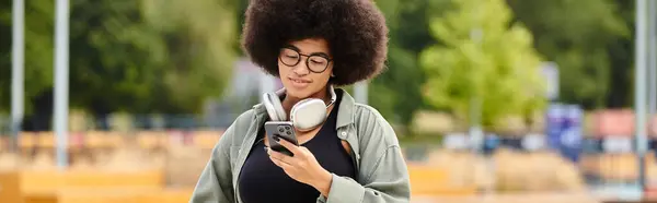 Una mujer con un cabello afro está usando un teléfono celular. - foto de stock