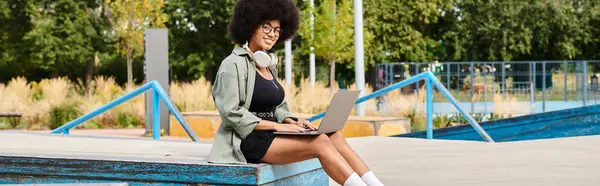 Uma jovem mulher se senta em um banco em um parque, absorvida em sua tela de laptop, encontrando inspiração e empoderamento. — Fotografia de Stock