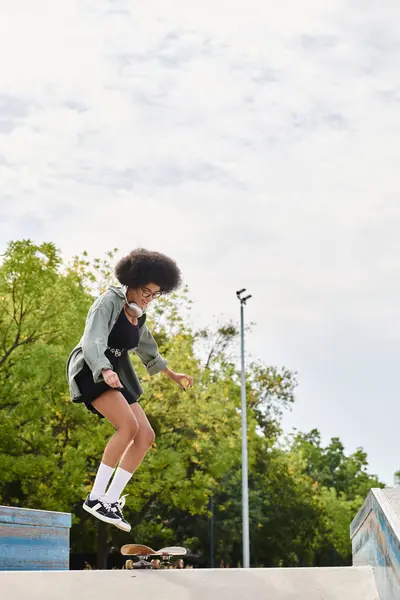 A young African American woman with curly hair skillfully skateboarding up the side of a ramp at an outdoor skate park. — Stock Photo