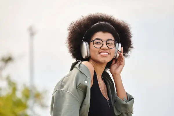 Стильна молода жінка насолоджується музикою у своїх навушниках, одягнувши модний піджак. — стокове фото