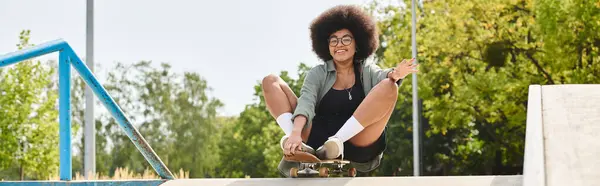 Young African American woman with curly hair enjoying an exhilarating skateboard ride down a ramp at a skate park. — Stock Photo