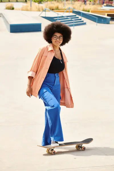 Jeune femme afro-américaine avec des cheveux bouclés équitation skateboard dans un parc animé, montrant compétence et liberté. — Photo de stock