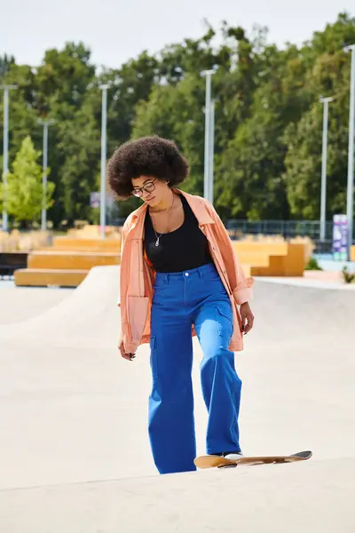 Jovem afro-americana com cabelo encaracolado executando truques em um skate em um parque de skate vibrante. — Fotografia de Stock