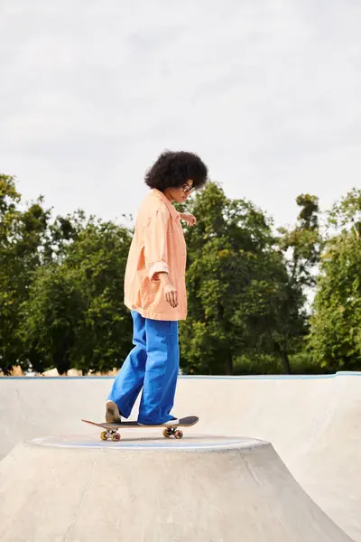 Young African American woman with curly hair showing off her skateboarding skills on a ramp at a skate park. — Stock Photo