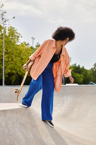 Eine junge Afroamerikanerin mit lockigem Haar skatet selbstbewusst auf einer Rampe in einem lebhaften Skatepark. — Stockfoto