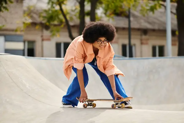 Young African American woman with curly hair gracefully skateboarding at a vibrant outdoor skate park. — Stock Photo