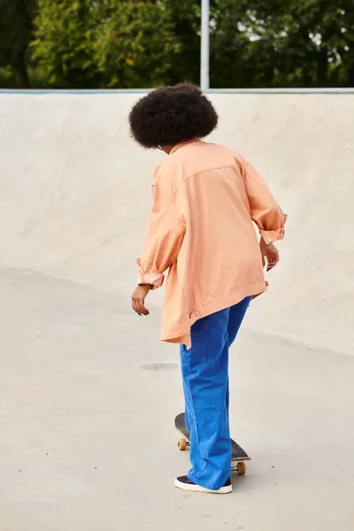 Eine Afroamerikanerin mit lockigem Haar fährt gekonnt ein Skateboard in einem Outdoor-Skatepark. — Stockfoto