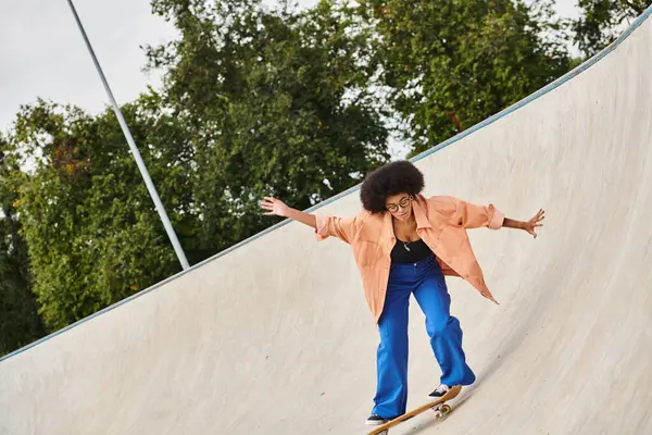 Eine junge Afroamerikanerin mit lockigem Haar fährt auf einem Skateboard die Seite einer Rampe in einem Outdoor-Skatepark hinauf. — Stockfoto