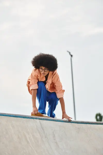 Молода афроамериканська дівчина впевнено стоїть на скейтборді, відточуючи свої навички в скейт-парку. — стокове фото