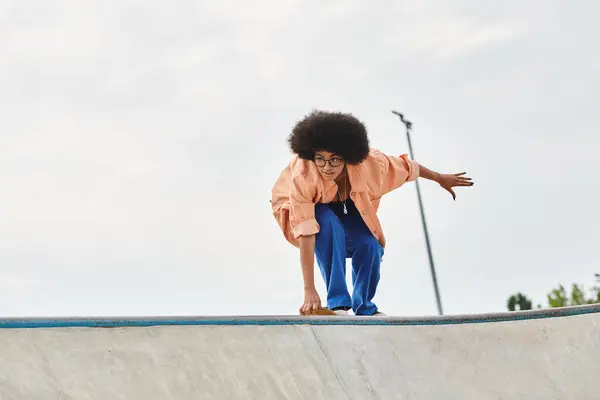 Молода афроамериканка з кучерявим волоссям катається на скейтборді на пандусі у відкритому скейт-парку. — стокове фото