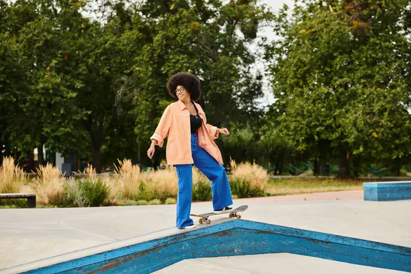 A young African American woman with curly hair rides a skateboard on a ramp at a skate park, performing daring tricks. — Stock Photo