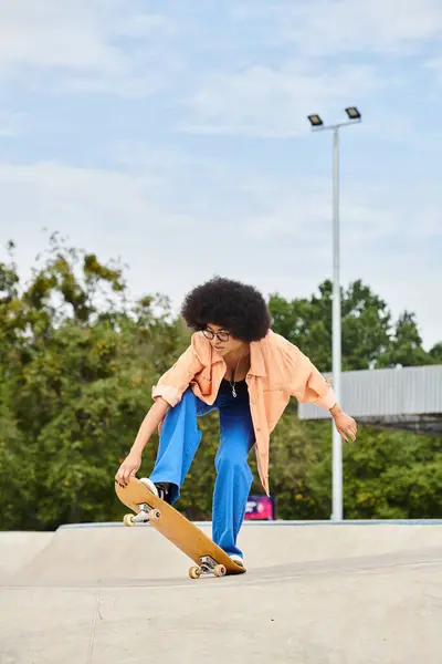A young African American woman with curly hair performing an impressive trick on her skateboard at a skate park. — Stock Photo