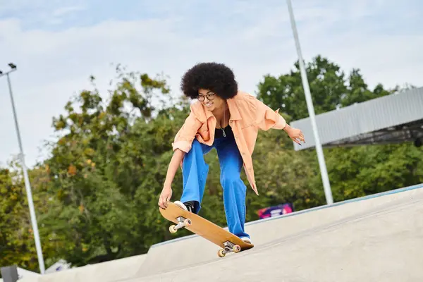 A young African American woman with curly hair skillfully performing a trick on a skateboard at an outdoor skate park. — Stock Photo