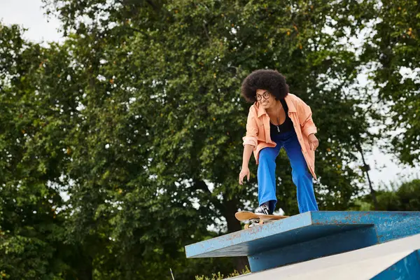 Jeune femme afro-américaine monte une planche à roulettes sur une rampe, montrant ses compétences et son courage dans une descente passionnante. — Photo de stock