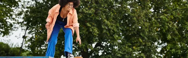Uma mulher afro-americana com cabelo encaracolado habilmente skate em cima de uma rampa em um parque de skate ao ar livre. — Fotografia de Stock