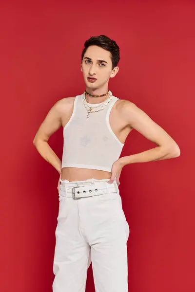 Good looking gay man in casual attire with accessories on red background and looking at camera — Stock Photo