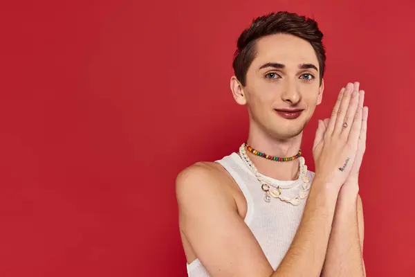 Alegre bonito gay homem com elegante acessórios no branco traje olhando para câmera no vermelho pano de fundo — Fotografia de Stock