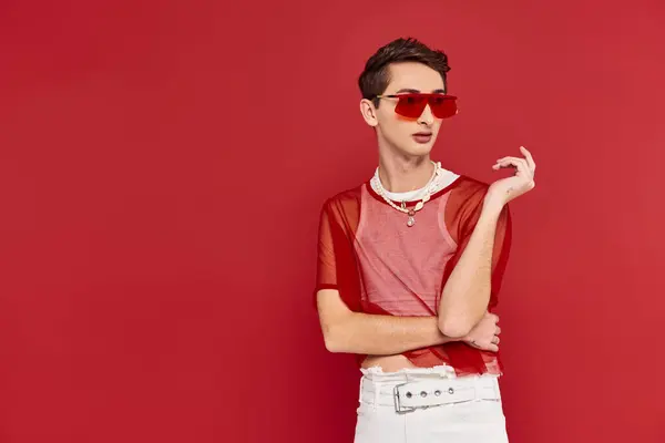 Sophisticated androgynous man with red stylish fishnet and sunglasses posing and looking away — Stock Photo