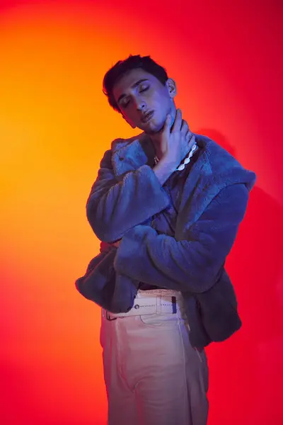Elegante seducente uomo androgino in eco pelliccia viola in posa con gli occhi chiusi su uno sfondo vibrante — Foto stock