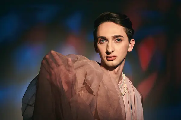 Enticing androgynous fashionista with dark hair in pastel attire looking at camera on vivid backdrop — Stock Photo