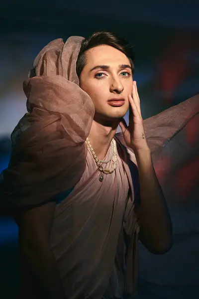 Voguish androgynous fashionista with dark hair in pastel attire looking at camera on vivid backdrop — Stock Photo