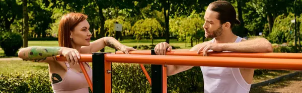 Un hombre y una mujer decididos en ropa deportiva están uno al lado del otro, motivados durante una sesión de entrenamiento al aire libre. - foto de stock