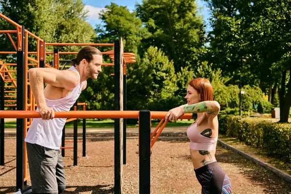 Uma mulher determinada em sportswear, liderada por um personal trainer, exercita-se em frente a um parque infantil. — Fotografia de Stock