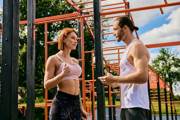 Un homme et une femme en tenue de sport se tiennent côte à côte, faisant preuve de détermination et de motivation alors qu'ils font de l'exercice à l'extérieur. — Photo de stock