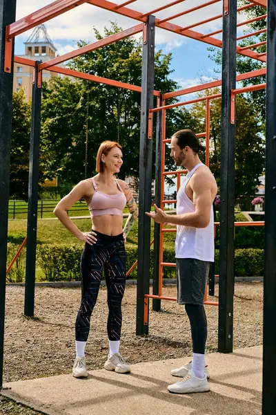Um homem e uma mulher no sportswear, estando ao lado um do outro, mostrando determinação e motivação enquanto exercitam ao ar livre, personal trainer. — Fotografia de Stock