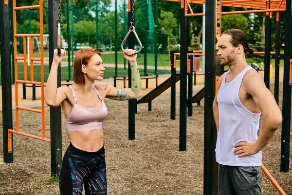 Un uomo e una donna in abbigliamento sportivo in piedi insieme in un parco, mostrando determinazione e motivazione — Foto stock