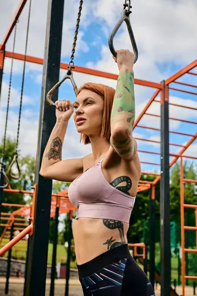 A determined woman in sportswear is doing a pull up on a bar outdoors — Stock Photo