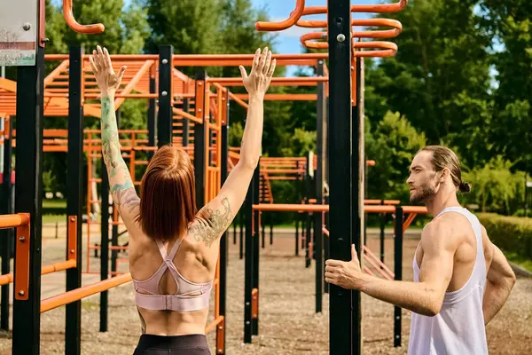 Une femme en tenue de sport exerce dans un parc avec détermination et motivation, guidée par un entraîneur personnel. — Photo de stock