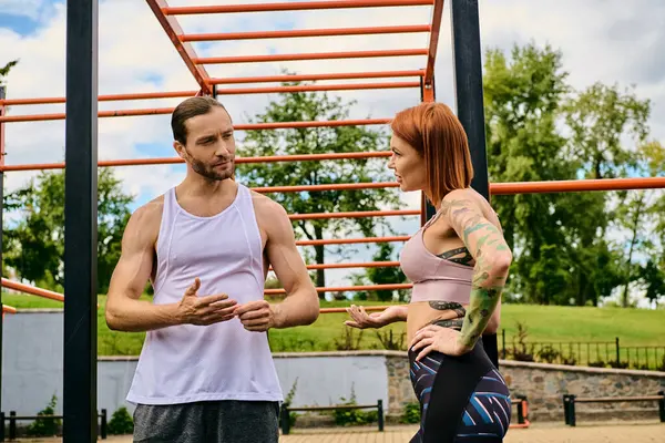 A woman in sportswear, guided by a personal trainer, display determination and motivation as they exercise outdoors together. — Stock Photo