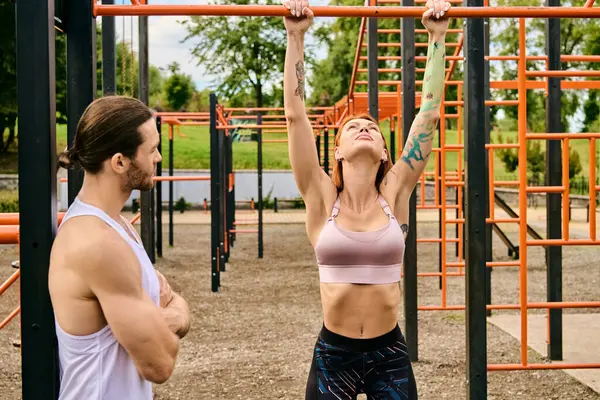 Un uomo e una donna in allenamento abbigliamento sportivo insieme sotto un cielo limpido di fronte a una palestra. Il personal trainer la motiva. — Foto stock