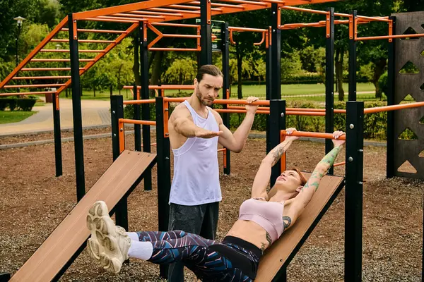 A woman in sportswear, led by a personal trainer, engaged in outdoor exercises with determination and motivation. — Stock Photo