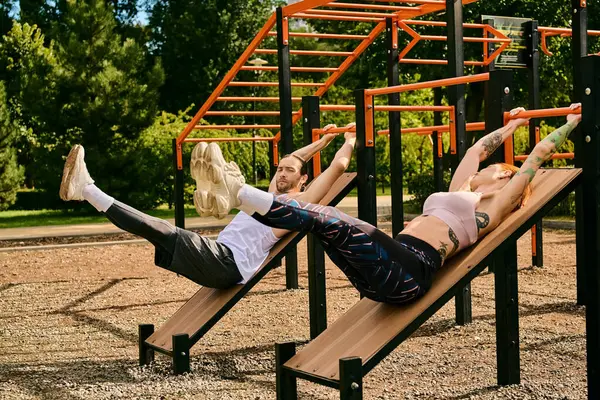 Un homme et une femme en tenue de sport s'allongeaient sur des bancs s'entraînant avec un entraîneur personnel, faisant preuve de détermination et de motivation. — Photo de stock